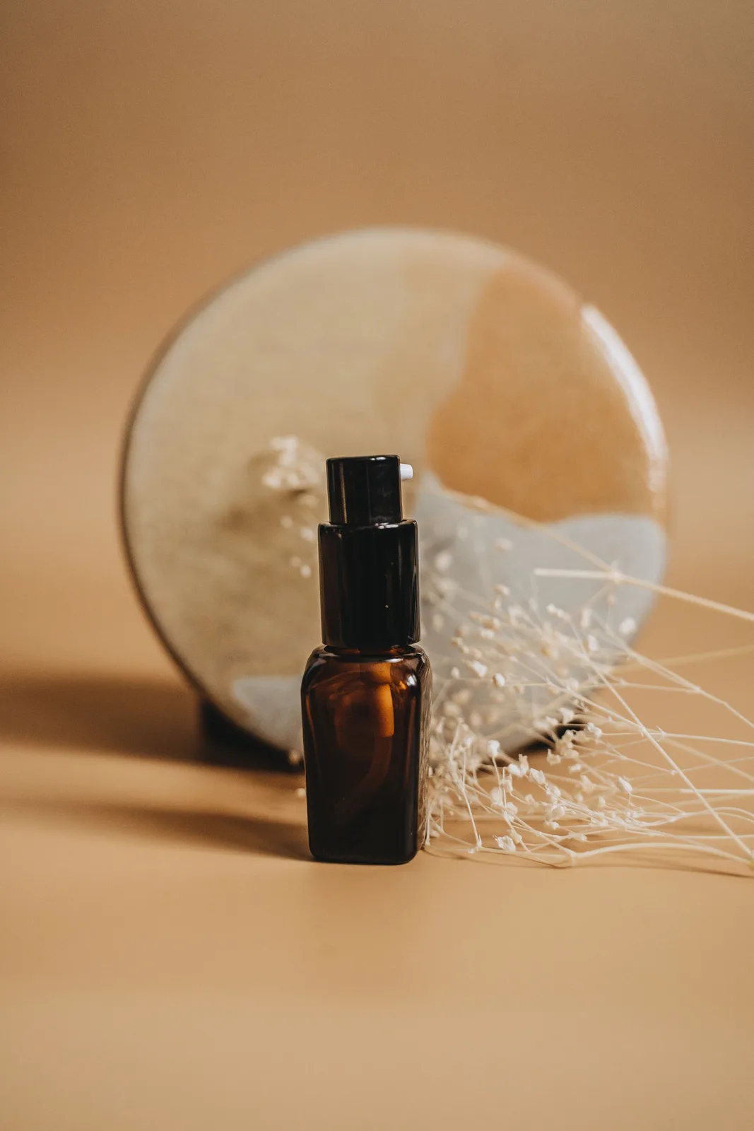 Envase ámbar con dosificador junto a elementos naturales